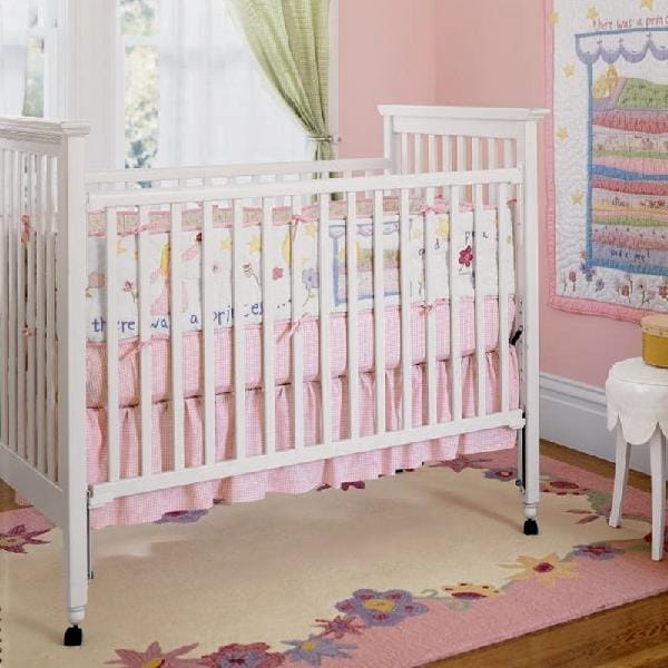 White baby crib with pink bedding and floral accents in a nursery, symbolizing crib safety concerns and recalls.