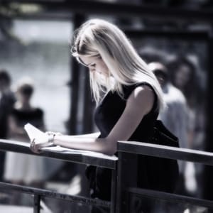 Young Woman Reading Outdoors – Birth Control Lawsuit Context - Ferraro Law Firm Young woman standing outdoors reading a document, symbolizing rising concerns and lawsuits related to birth control complications.