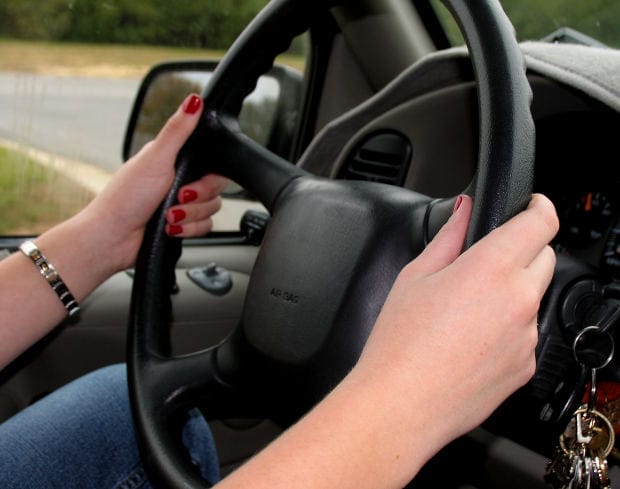 Holding Car Steering Wheel - Ferraro Law Firm Close-up of a person’s hands gripping a black car steering wheel with a key in the ignition.