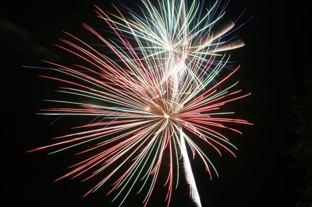 Large red, green, and blue fireworks bursting in the night sky, representing celebrations that can sometimes lead to injuries caused by negligence or defective products.
