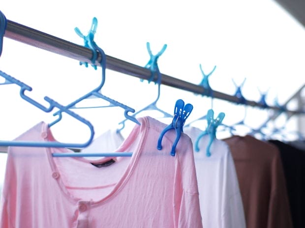 Pink shirt and other clothing hanging on a clothesline with blue plastic