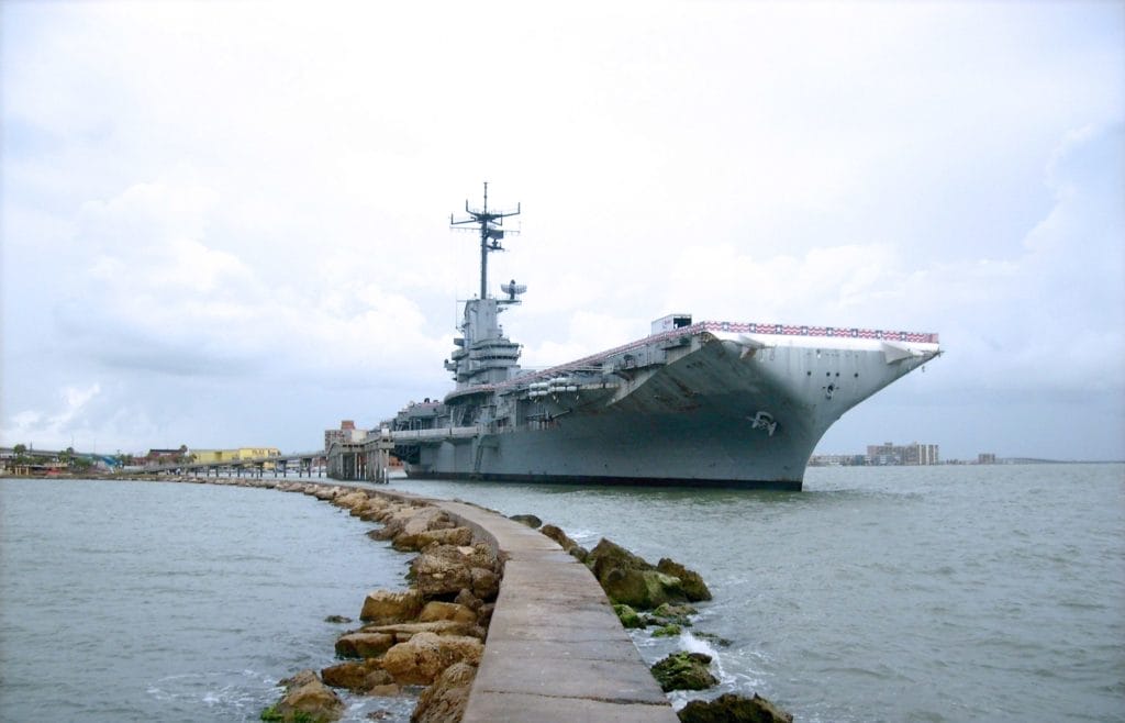 Large U.S. Navy aircraft carrier docked at port, symbolizing asbestos exposure risks for sailors and shipyard workers.