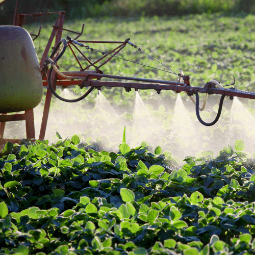 Close-up of agricultural sprayer applying herbicide to crops, representing paraquat exposure risks linked to Parkinson’s disease.