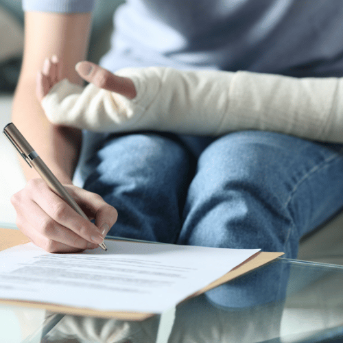 Person with an arm cast signing legal documents, symbolizing the process of hiring a tractor trailer accident attorney after sustaining serious injuries in a crash.
